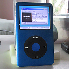 an IPod mp3 player, a rectangular slab of metal with a rectangular screen with a touch sensitive wheel below for controls.