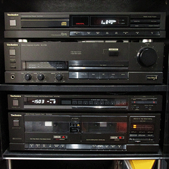 an old-looing collection of grey boxy hi-fi units, covered in various switches, buttons and dials.