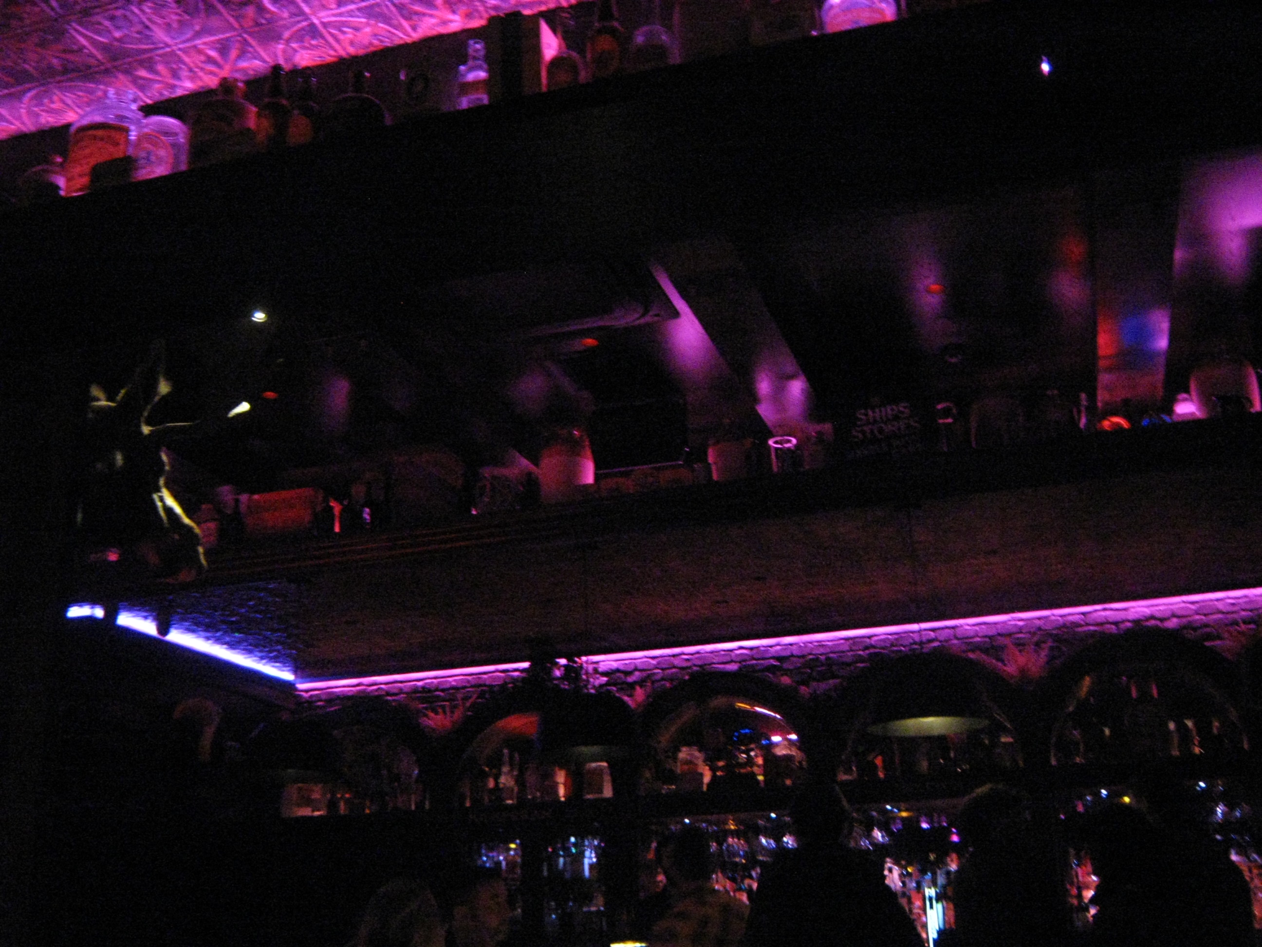 Small picture of a bar, dimly lit but purple glowing lights in the ceiling